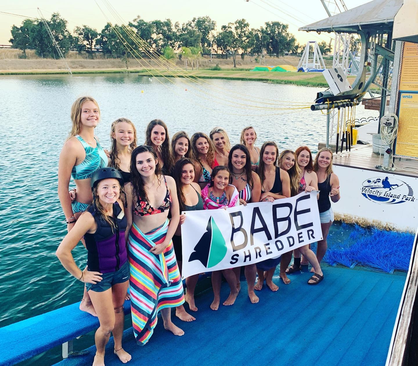 Women gathered on a watersports dock with a Babeshredder banner