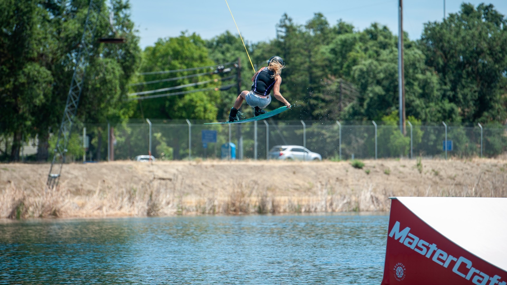 Ash catching air on a wakeboard at a cable park